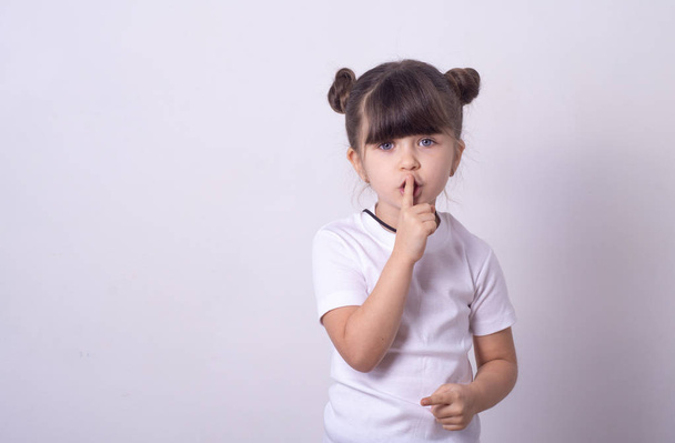 Shhh znamení. Mladá dívka ukazuje Ššš gesto aby tiché. Dívka v šabloně bílé tričko t držet v tajnosti. Kopírovat prostor  - Fotografie, Obrázek