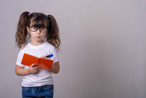 Niedliches Kind trägt Brille mit Stiften und Schreibidee im Notizbuch.  - Foto, Bild