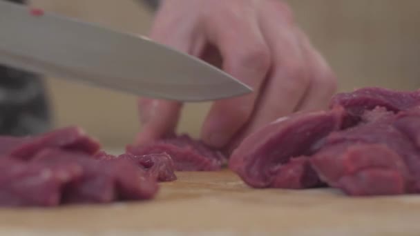 Chef hands cutting meat with big knife in the kitchen close up. Man cutting pork beef on chopping board. Food sliced pieces raw meat - Video