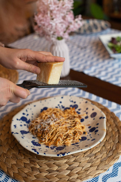 woman hands grating parmesan cheese to homemade spaghetti bologn - Photo, Image