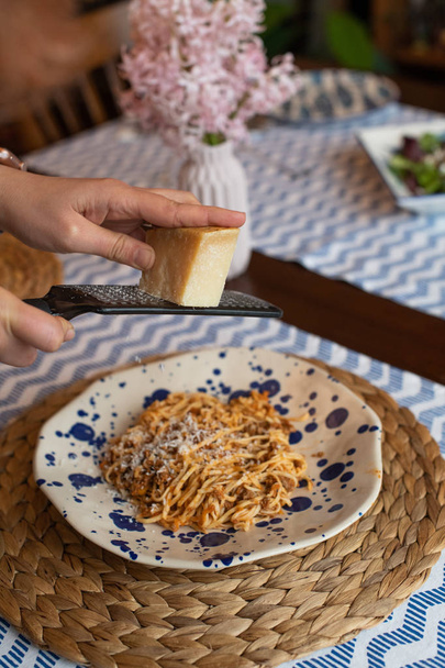 Frau reicht geriebenen Parmesan zu hausgemachten Spaghetti Bologn - Foto, Bild