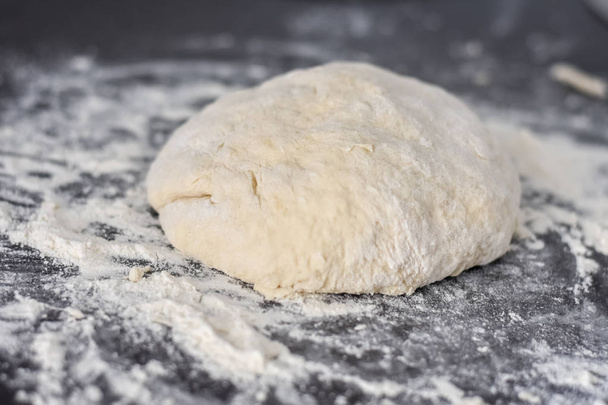 dough on a black table, homemade food - Foto, afbeelding