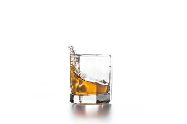 Salpicadura de whisky en vidrio con hielo sobre fondo claro
 - Foto, imagen