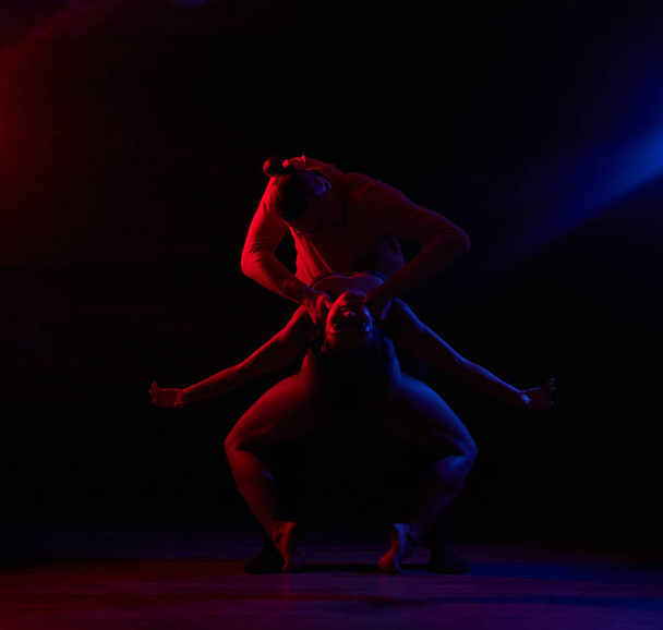 Beautiful couple dancing on the dance floor in a night club. Dancers performing in the dark with illumination - Foto, Imagem