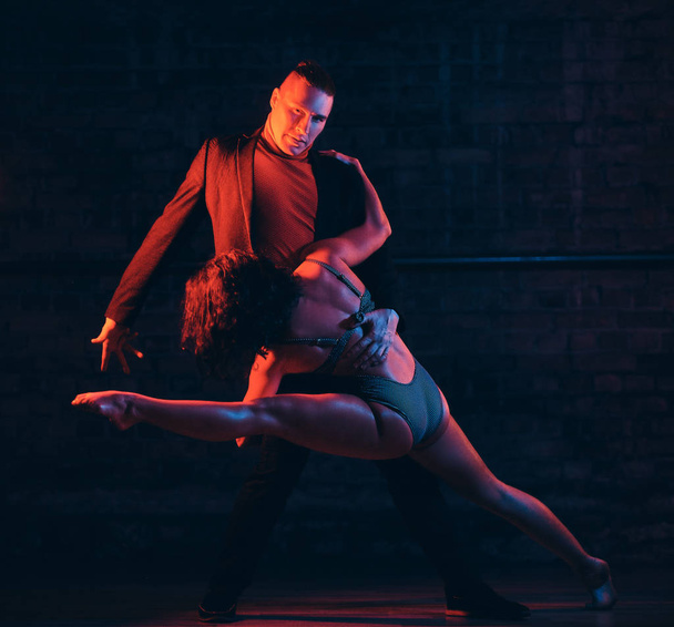 Beau couple dansant sur la piste de danse dans une boîte de nuit. Danseurs jouant dans le noir avec illumination
 - Photo, image