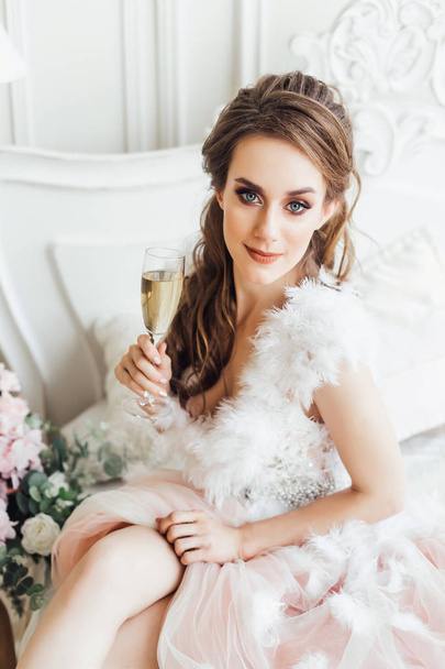 Young woman with glass of champagne in chair in stylish interior - Фото, изображение