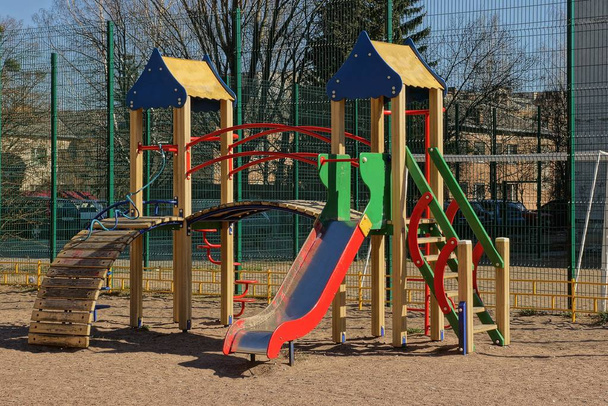 playground com slide colorido e edifícios fora
 - Foto, Imagem