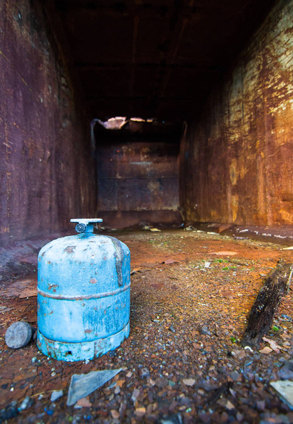 Um tanque de gás fica dentro de um velho contentor enferrujado
 - Foto, Imagem
