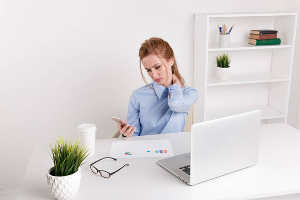 Büroangestellte sitzt an ihrem Arbeitsplatz vor dem Computer und spürt Nackenschmerzen. trauriger Arbeiter, der sich verärgert und müde fühlt. - Foto, Bild