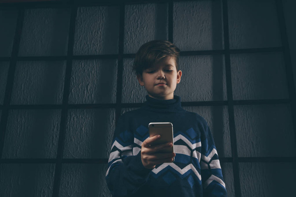 Teen chłopiec trzyma telefon i smutna. Ofiarą cyberprzemocy. Znęcanie się telefon. - Zdjęcie, obraz