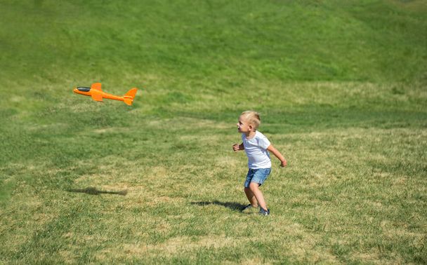 Young boy playing airplane on the meadow - Φωτογραφία, εικόνα
