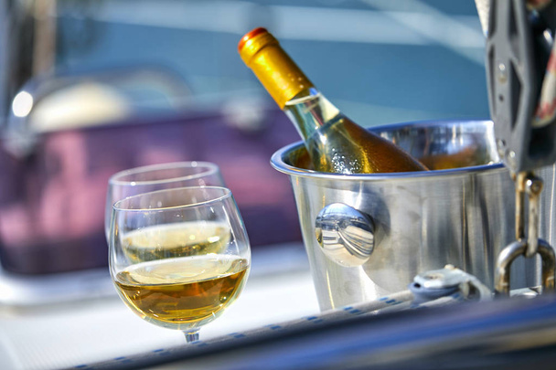 Pair of wineglasses and bucket with white wine bottle on yacht - Photo, Image