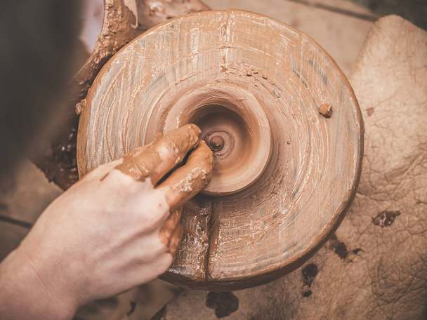 上から撮影したそれにポッターズ ホイールと粘土焼を回転します。A sculpts 陶工の車輪の上に粘土カップの彼の手。粘土の手。陶器男性陶芸家手作り粘土製品を作成します。プロセス - 写真・画像