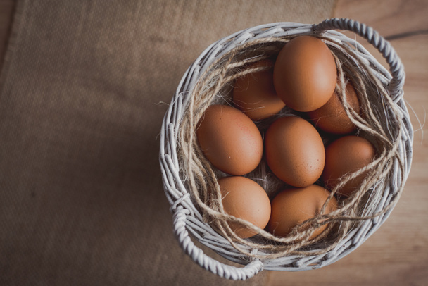 Huevos frescos en canasta de mimbre en la mesa de madera Preparar huevos de pollo y batidor de huevo para cocinar o panadería puede utilizar para fondo o papel pintado
 - Foto, imagen