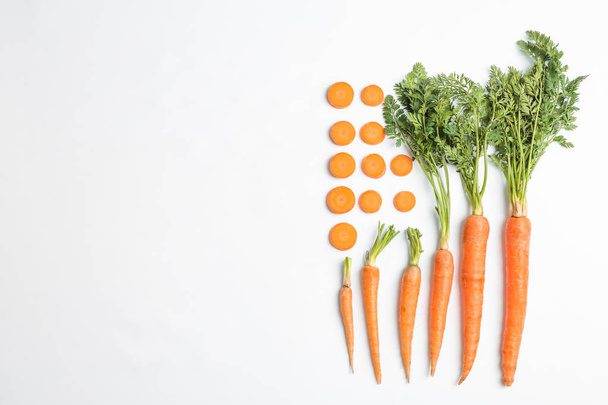Επίπεδη lay σύνθεση με ώριμα φρέσκα καρότα σε λευκό φόντο - Φωτογραφία, εικόνα