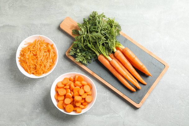 Cutting board with ripe carrots on grey table, space for text - Photo, Image