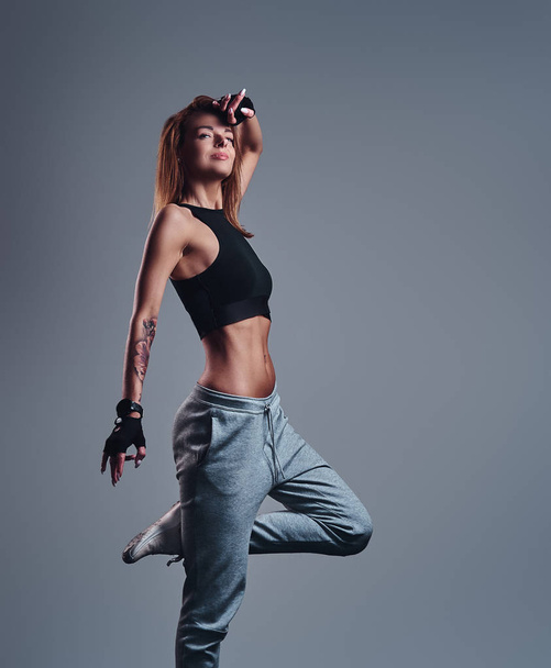 Full-length portrait of a slim fitness girl wearing sportswear posing in a studio. - Photo, Image