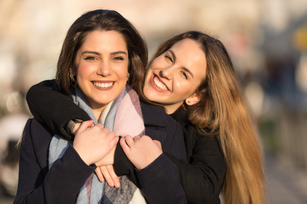 Young pretty girls best friends smiling and having fun, walking at the city. Shopping. Wearing stylish outerwear. Bright make up. Positive emotions. Outdoors lifestyle fashion close up portrait - Photo, Image
