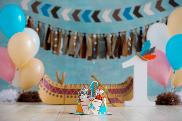Decorated photo zone for 1 year Indian Apache chief with a canoe for a childrens party. First birthday and smash cake - Foto, immagini