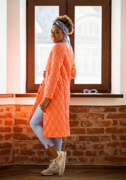 African model woman in orange spring jacket and blue pants  - Фото, изображение