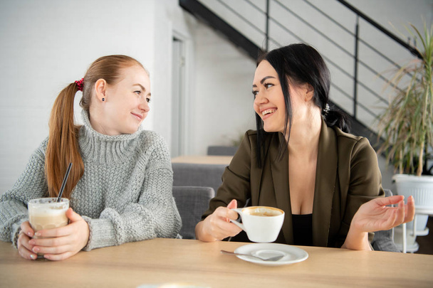 Δύο νέοι και όμορφες γυναίκες ανταποκρίνονται στο μπαρ για έναν cappuccino και να συνομιλήσετε. - Φωτογραφία, εικόνα