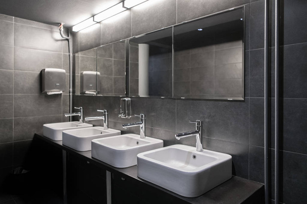 グレー色の公衆トイレの洗面台と水栓 - 写真・画像