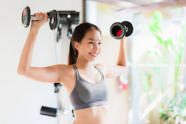 Портрет красивая молодая азиатка упражнения с фитнес-оборудования в тренажерном зале интерьера для хорошего здоровья
 - Фото, изображение