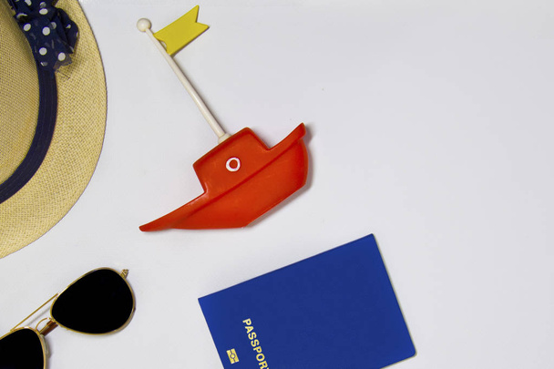 Sea sunglasses, passport, toy boat, hat on a light background with sand, top view - Foto, Imagen