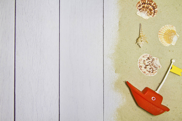 Sea shells, stars, toy boat on a light wooden background with sand, top view - Φωτογραφία, εικόνα