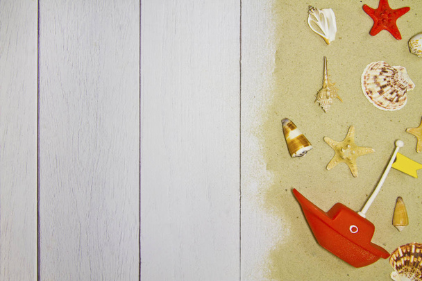 Tengeri kagyló, csillag, játék hajó, a világos fából készült háttér homokkal, felülnézet - Fotó, kép
