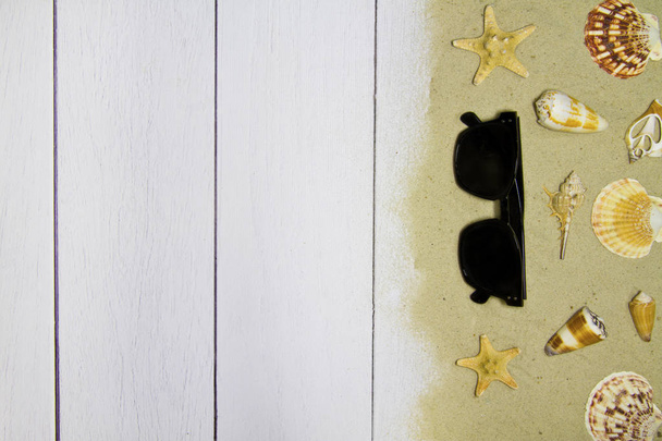 Conchas do mar, estrelas, óculos de sol em um fundo de madeira leve com areia, vista superior
 - Foto, Imagem