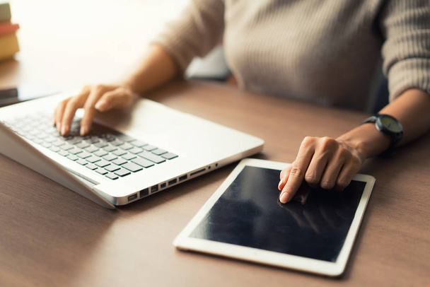 Donna che utilizza laptop e tablet digitale durante il lavoro in ufficio
,  - Foto, immagini