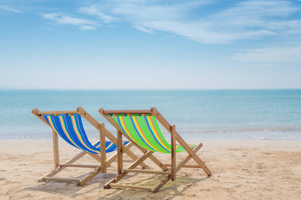 Duas cadeiras de praia na areia branca com céu azul e mar de verão
  - Foto, Imagem