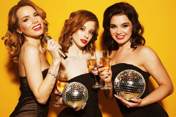encantadoras mujeres jóvenes con bolas de discoteca beber champán
 - Foto, imagen