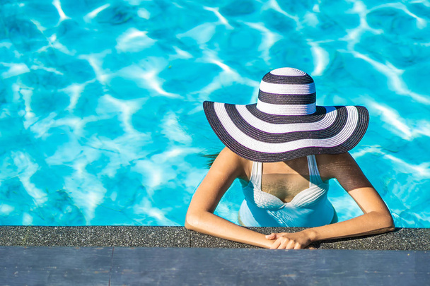 Gyönyörű fiatal ázsiai nő kalapban medencében, utazás, nyaralás koncepció - Fotó, kép