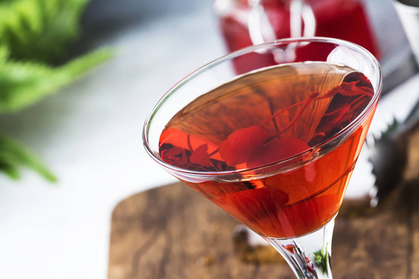 Classic alcoholic cocktail Manhattan with bourbon, red vemuth, bitter, ice and cocktail cherry in glass, gray bar counter background, place for text, selective focus - Foto, Imagem