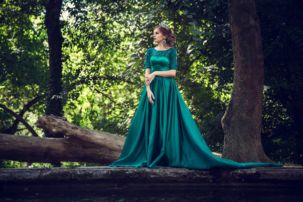 Fiatal nő, fárasztó egy zöld ruhát tárja fel a varázslatos erdő - Fotó, kép