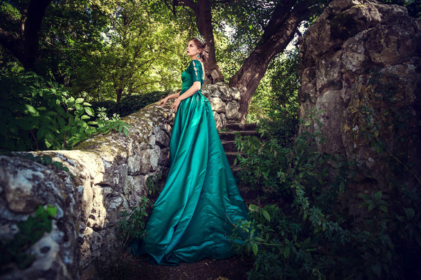 Jovem usando um vestido verde explora uma floresta mágica
 - Foto, Imagem