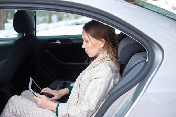 Attractive executive female manager working with a tablet in a backseat of a car - Foto, imagen