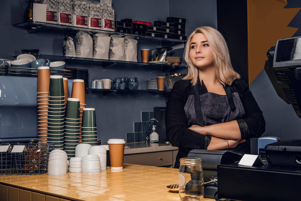 Női barista jelentő keresztezett karokkal, és néz körül egy kávézóban, vagy kávézóban - Fotó, kép