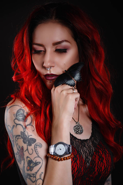 Zbliżenie piękna kobieta z tatuażem na sobie dżinsy krótkie malowania czarnym tle. - Zdjęcie, obraz