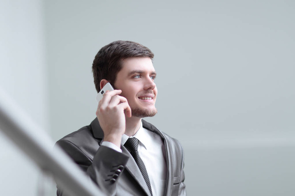 close up.smiling businessman talking on smartphone in office - Фото, изображение