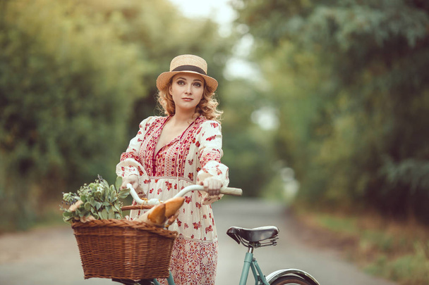Pregnant girl retro French style with bicycle on a forest road - Фото, изображение