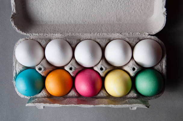 Os ovos de Páscoa são multicoloridos e brancos em uma bandeja de ovos. Vista superior. Preparação para o feriado de Páscoa
 - Foto, Imagem