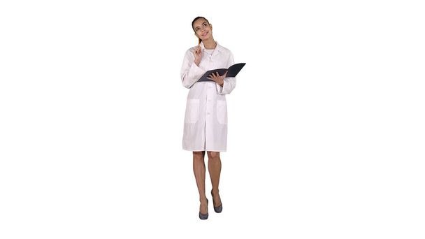 Expressive young female doctor with creative idea holding notebook and walking on white background. - Foto, afbeelding