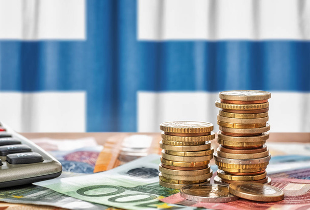 Billets et pièces en euros devant le drapeau national du Finlan
 - Photo, image