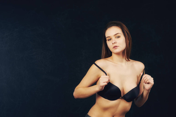 portrait of young beautiful woman in bra on dark background . - Fotó, kép