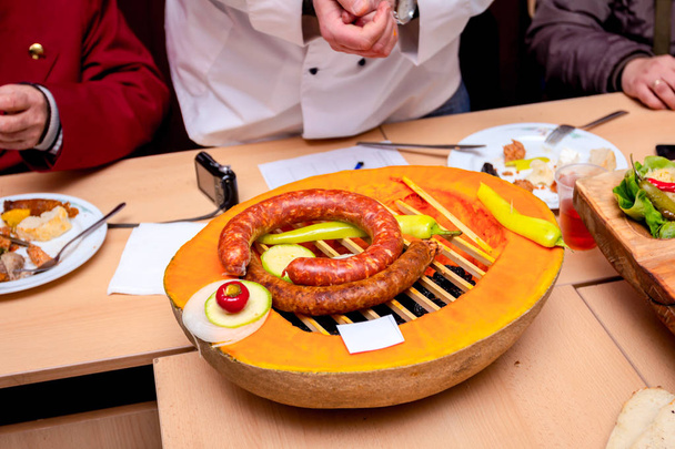 Traditional sausages with vegetables are decorated on a pumpkin  - Photo, Image