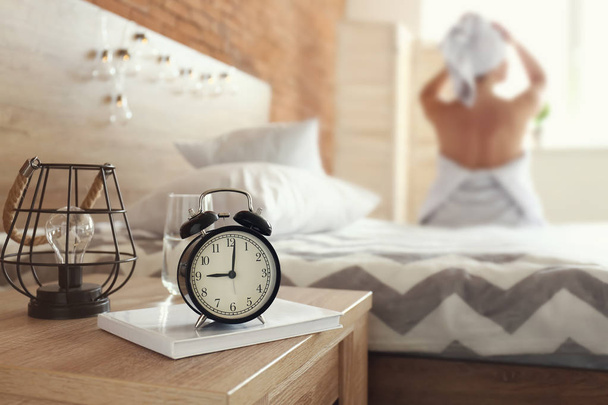 Alarm clock on table in bedroom of young woman - 写真・画像