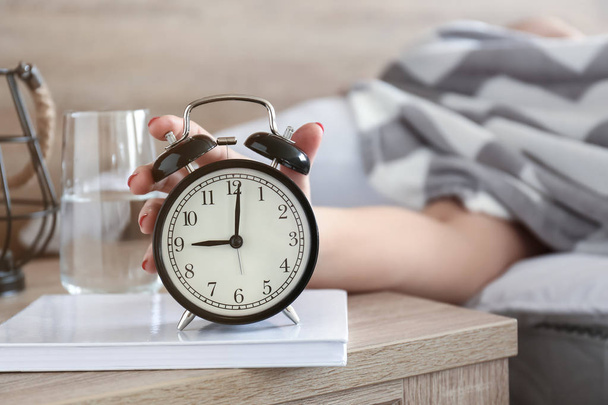 Сонная женщина выключает будильник утром - Фото, изображение